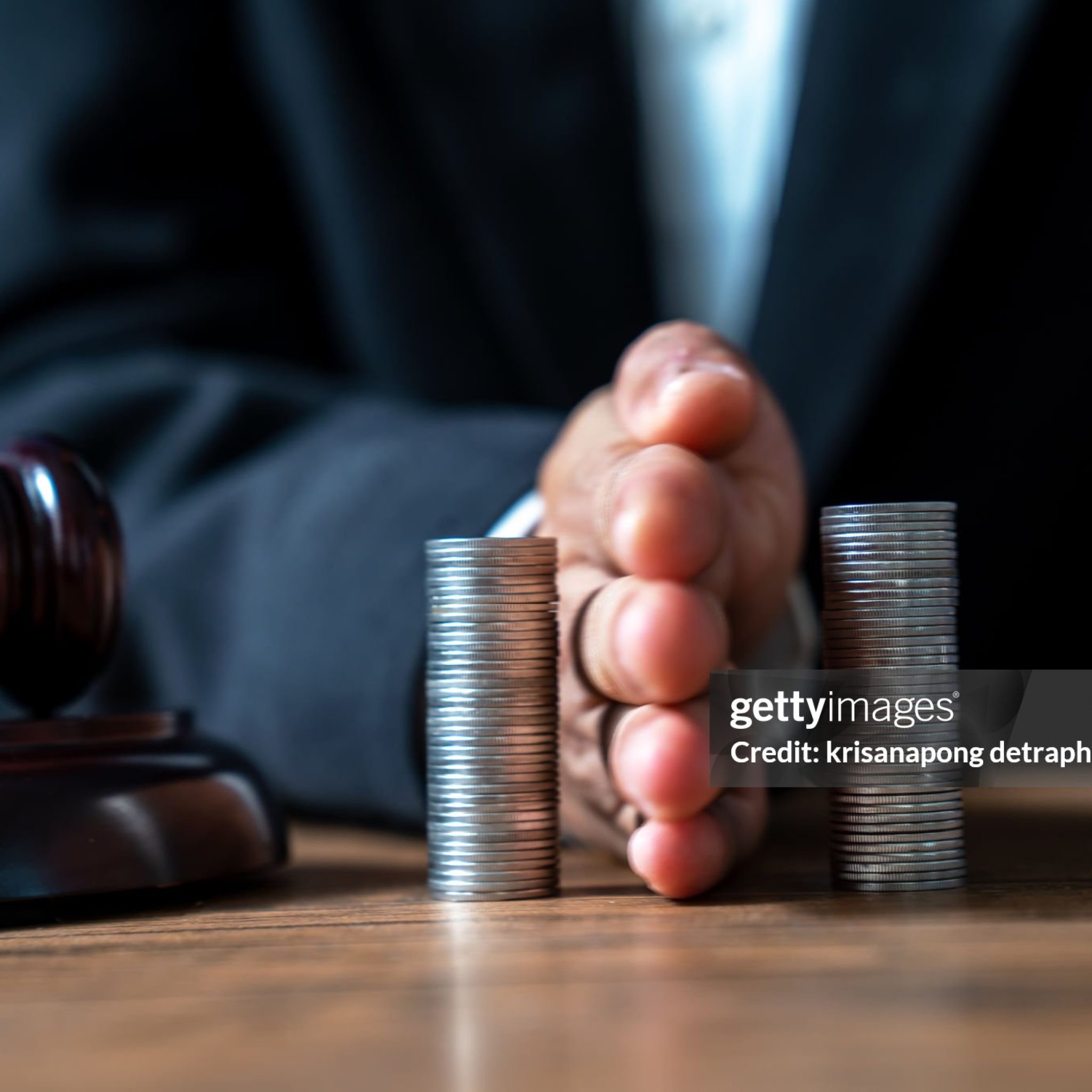 Concept of saving money and investment growth. Lawyer's hand holding coins on a pile of coins. Division of assets.,Concept of saving and investing.