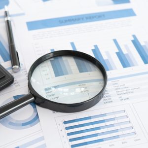 business and investment planning. Magnifying glass with business report on financial advisor desk. Concept of data analysis, accounting,audit, business research.